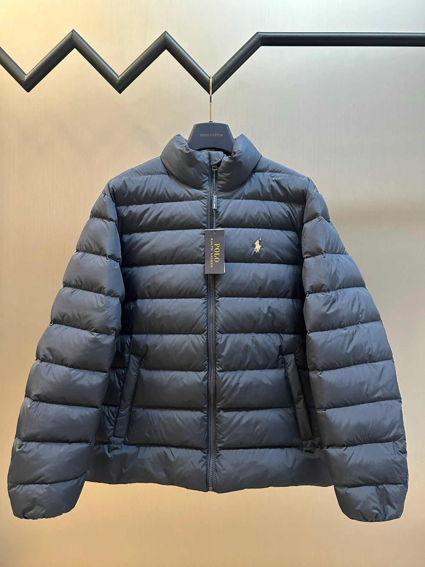 P890 Ralph Lauren lightweight down jacket. The nylon fabric has good windproof and waterproof properties, which can effectively block the intrusion of wind and rain from the outside and keep the inside dry. It is suitable for wearing in humid or rainy environments. The red label on the chest is made with an imported MECLO embroidery machine. The original pattern is scanned first, and then high-quality silk thread is used to make a pattern. The density effect is adjusted by continuous pattern making.  The zipper design is simple and elegant, easy to operate, and the closing design of the cuffs and hem effectively prevents cold wind from invading, improving the warmth and comfort of wearing. It uses 90 white duck down with a weight of 260g to ensure excellent thermal insulation performance. After strict screening and processing, the velvet is not easy to drill, ensuring durability. size: s m l xl